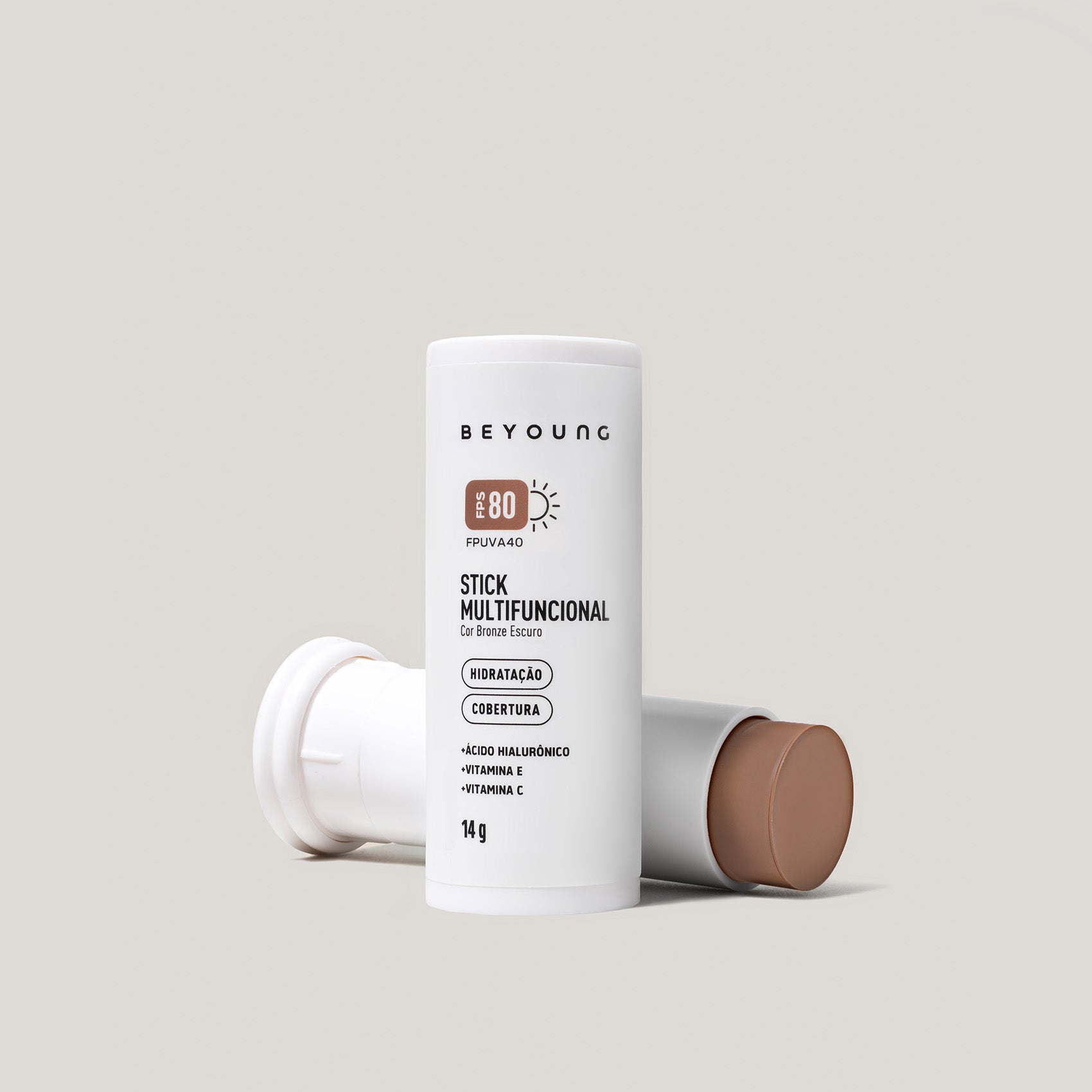 Stick Multifuncional Beyoung FPS 80 cor bronze escuro em embalagem branca, com ácido hialurônico, vitamina E e vitamina C.